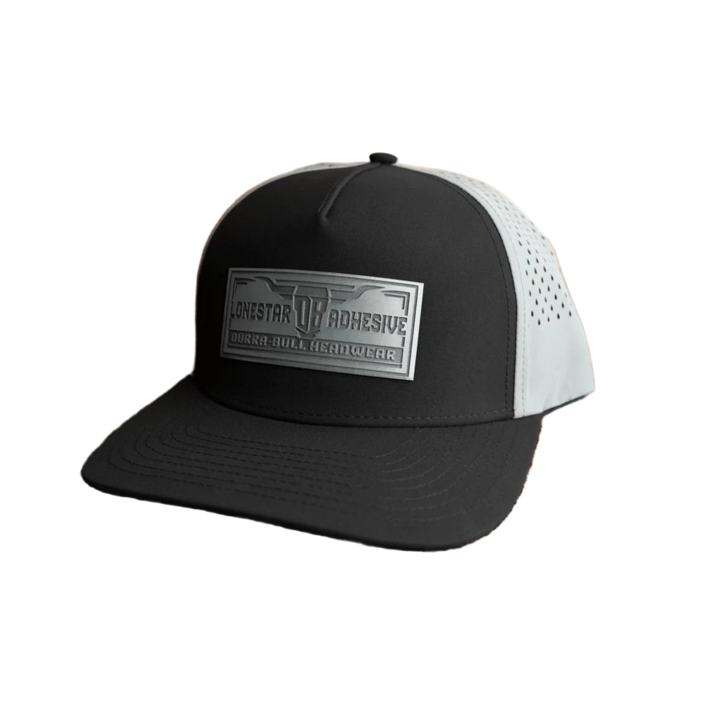 Black and charcoal cap with a brand logo on a wooden surface with ocean view